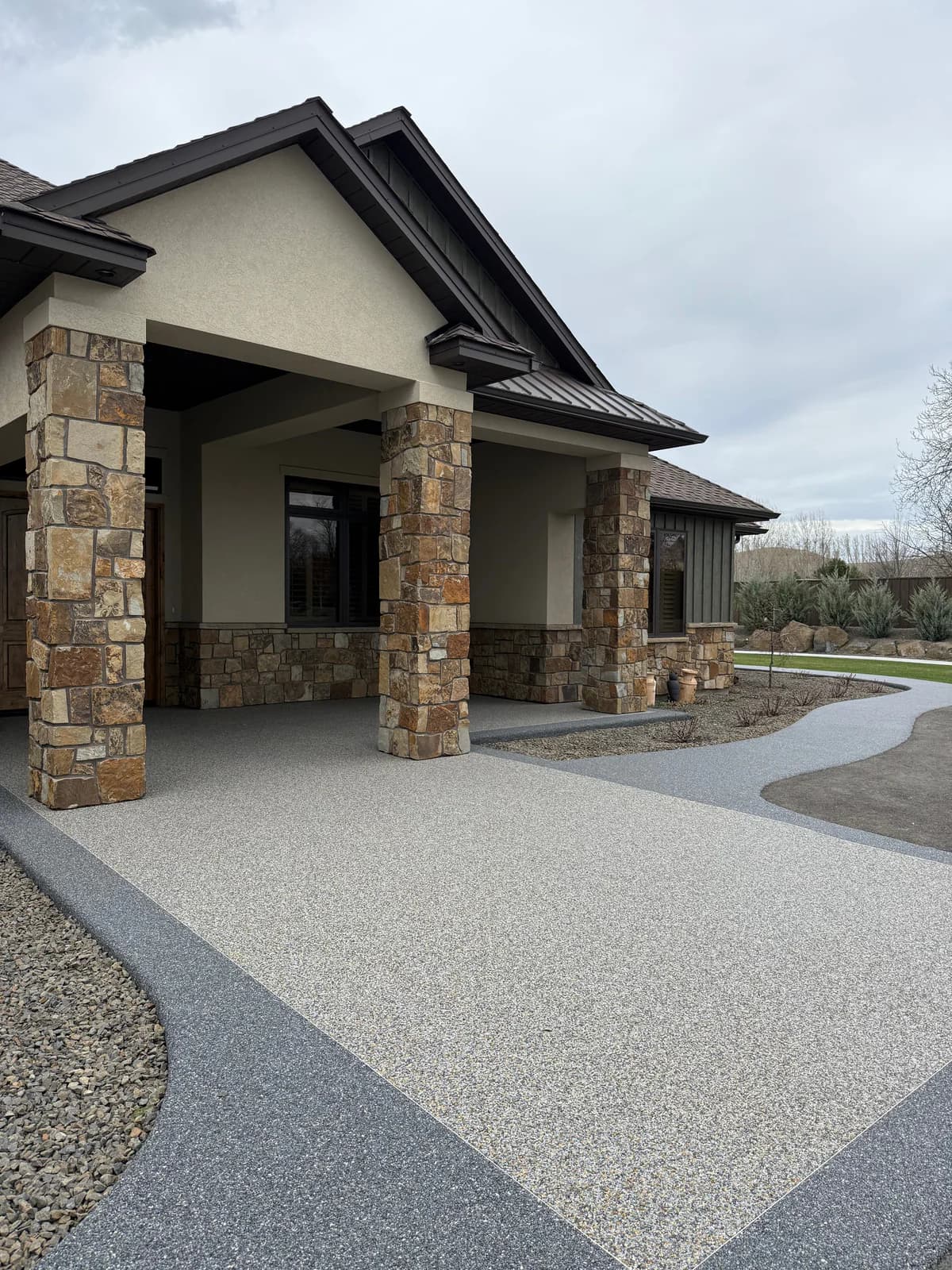 Resin‑bound entrance with contrasting border and stone pillars