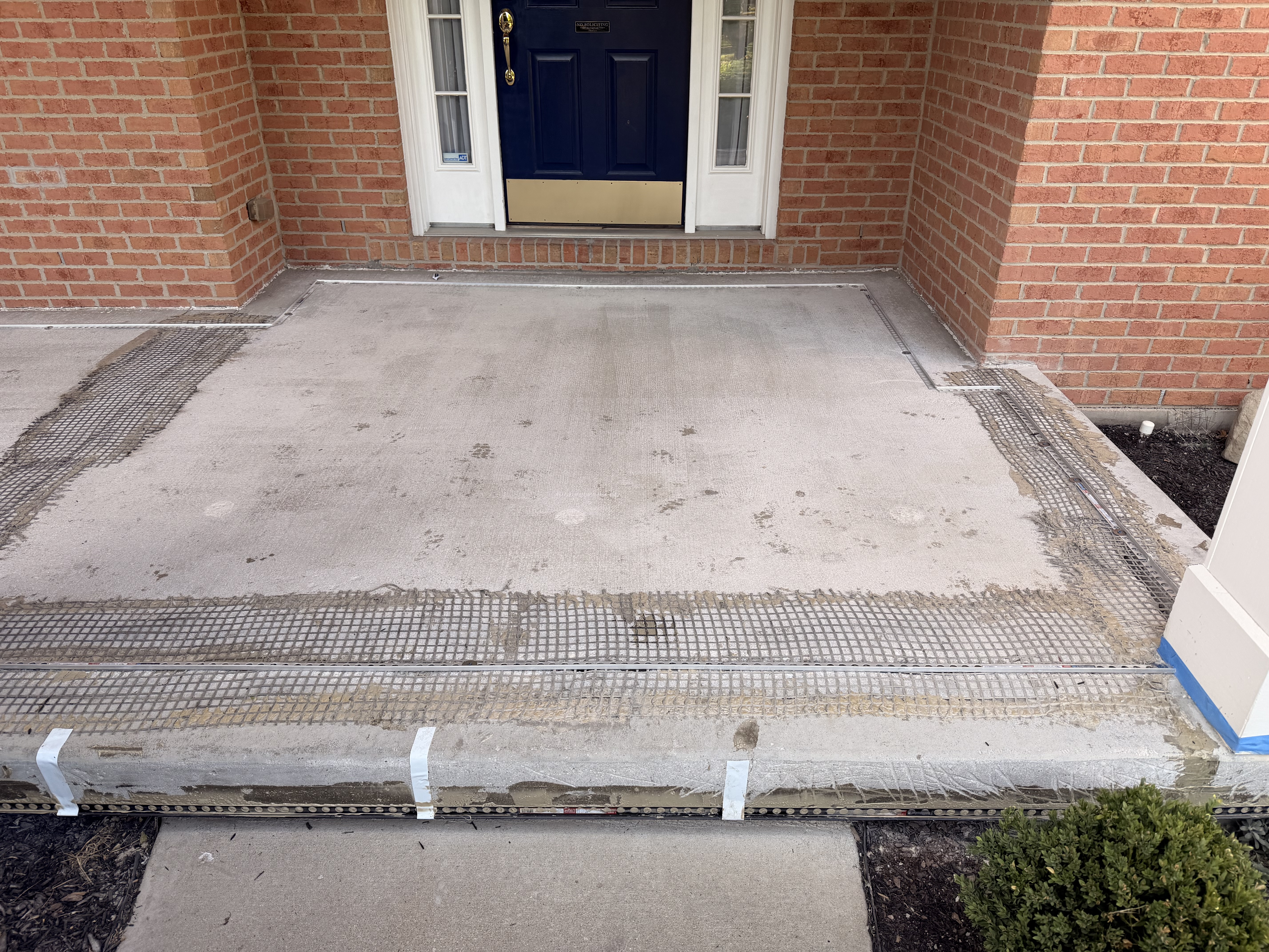 Mason covered front porch before resurfacing—worn concrete at the front entry
