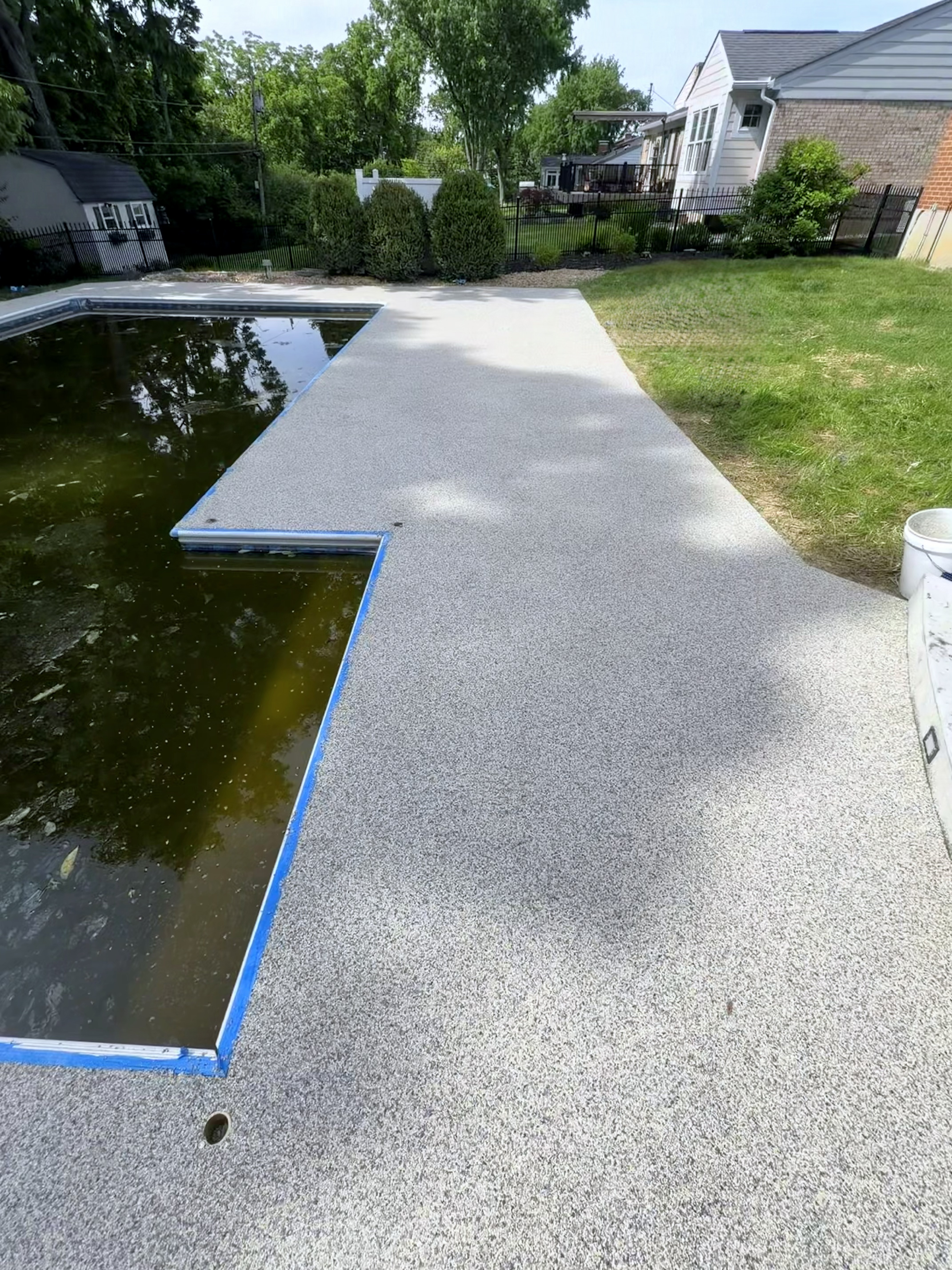 Sharonville pool deck after resin-bound stone flake finish with blue edge tape at the pool